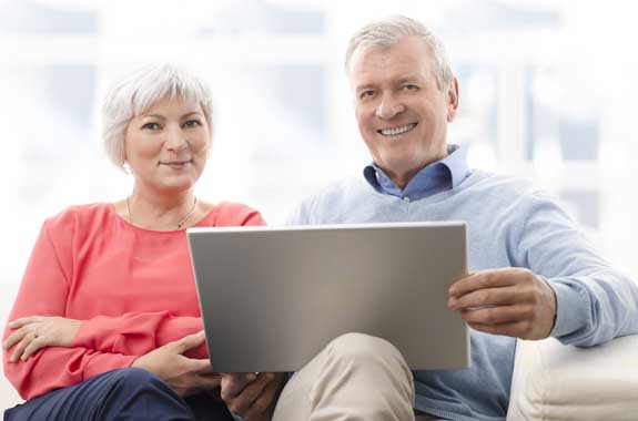 Neuer Job über 50: Paar mit grauen Haaren arbeitet an einem Laptop