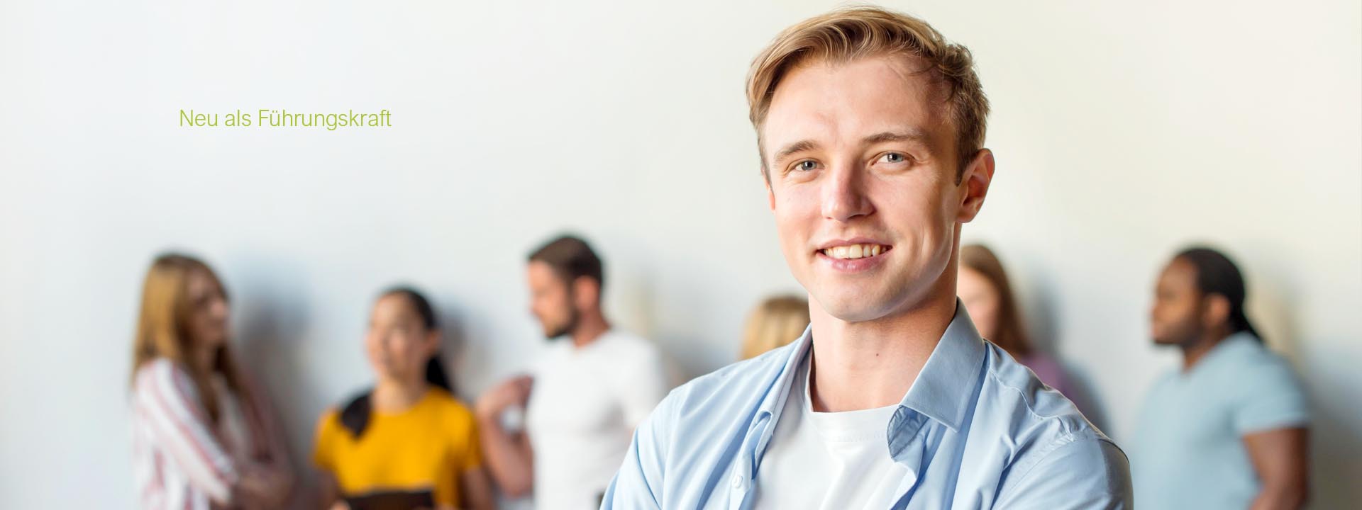 Junger Mann steht für einer Gruppe von Mensche - Coaching für die ersten 100 Tage als Führungskraft